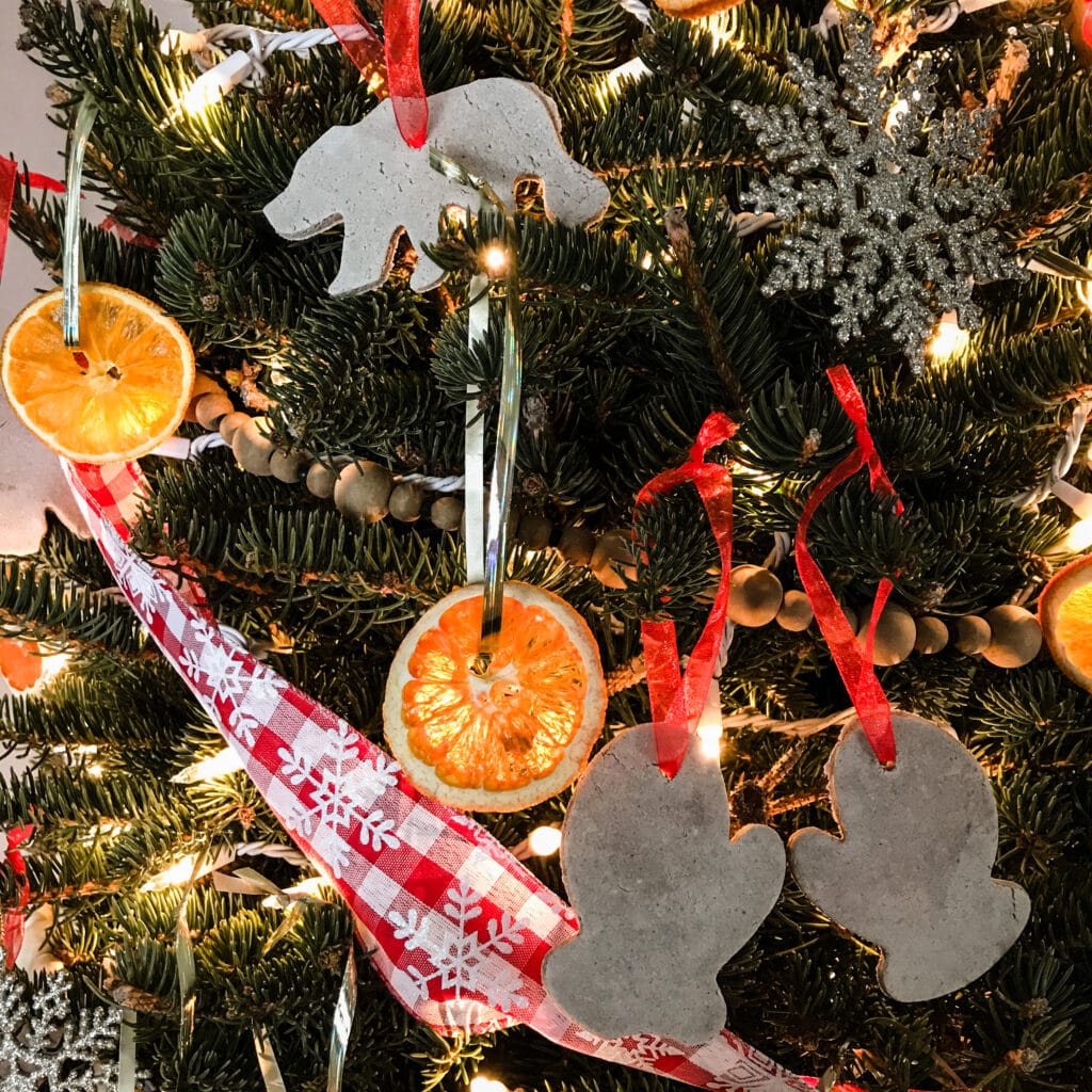 Close-up of Christmas tree showing hanging salt dough ornaments, dried oranges, and a red and white gingham ribbon