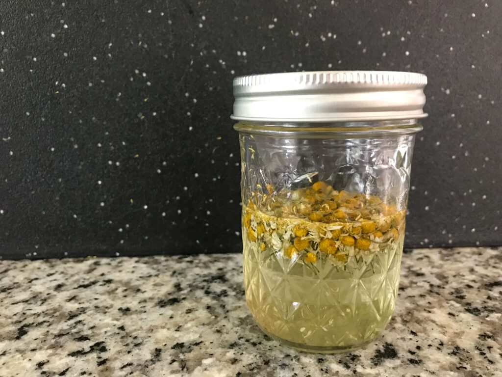 Image of a small jar of chamomile tincture on a black background