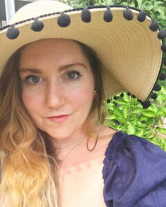 Selfie of the author wearing a blue dress and a floppy sun hat