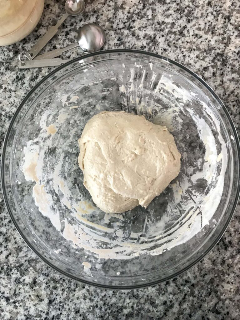 Overhead shot of a glass bowl containing the sourdough pizza crust dough after the first stretch and fold