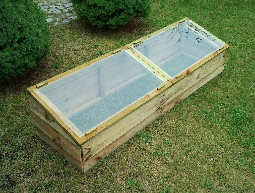 Two wooden, window-topped cold frames sit on grass – extend the growing season