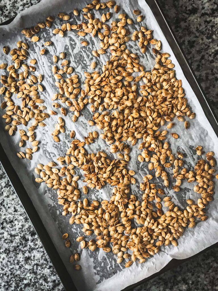 Overhead shot of roasted pumpkin seeds on a parchment-lined cookie sheet