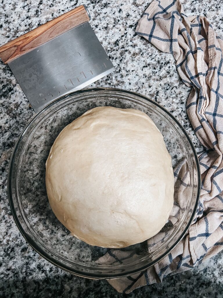 Overhead shot of proofed sourdough cinnamon roll dough right before rolling and filling
