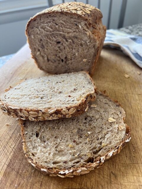 Close-up of the multigrain version of sourdough sandwich bread. Two slices have been cut so you can see the multigrains in the bread as well as the oats pressed on top.